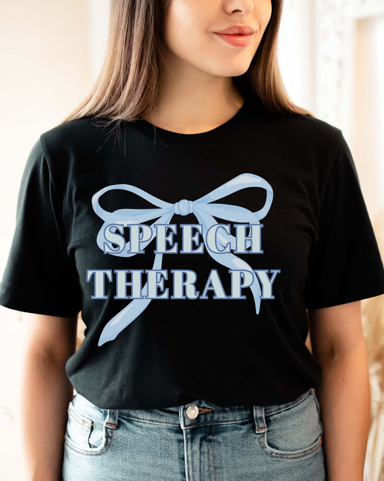 Person wearing a black t-shirt with 'Speech Therapy' and a bow design.